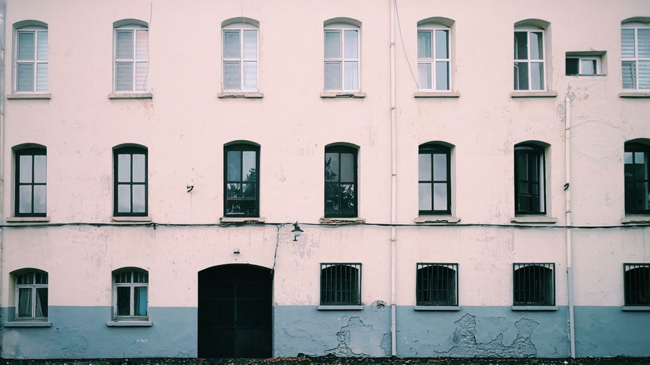 Front of a painted house with evenly spaced windows.