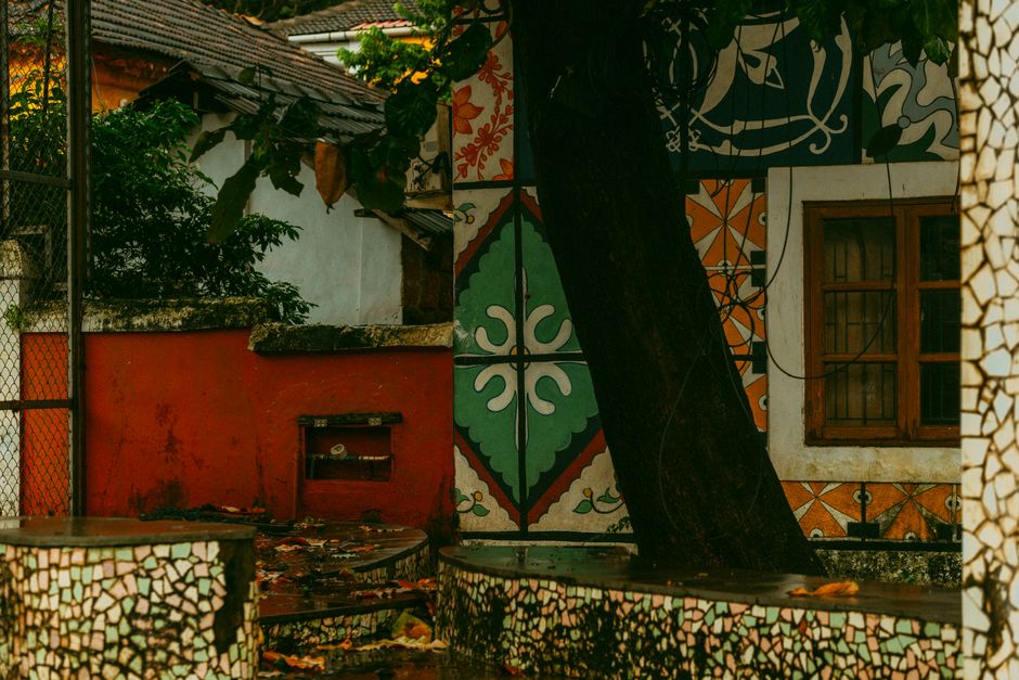 Painted exterior wall with colour samples and a tree in front.