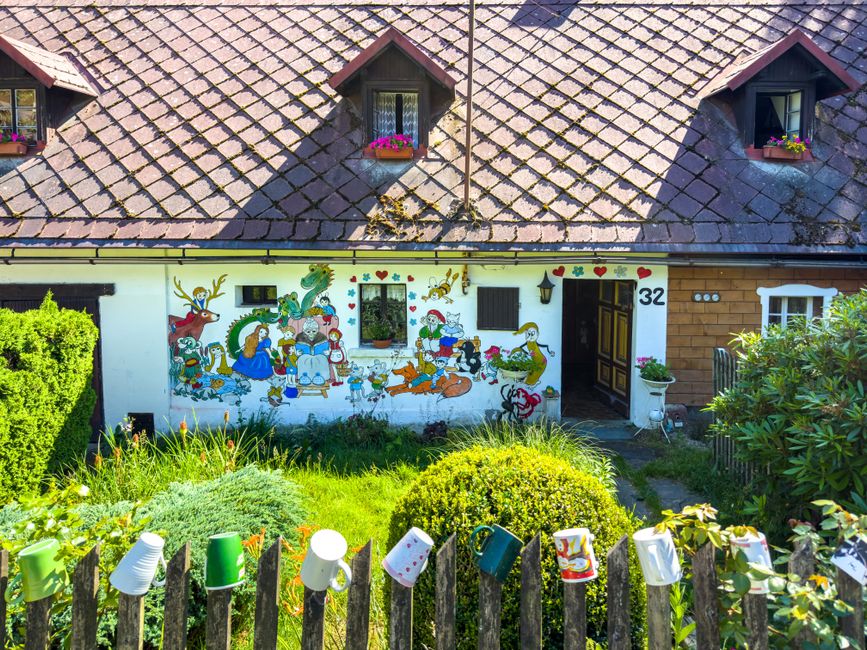 Painted house front with a small yard and flowers.