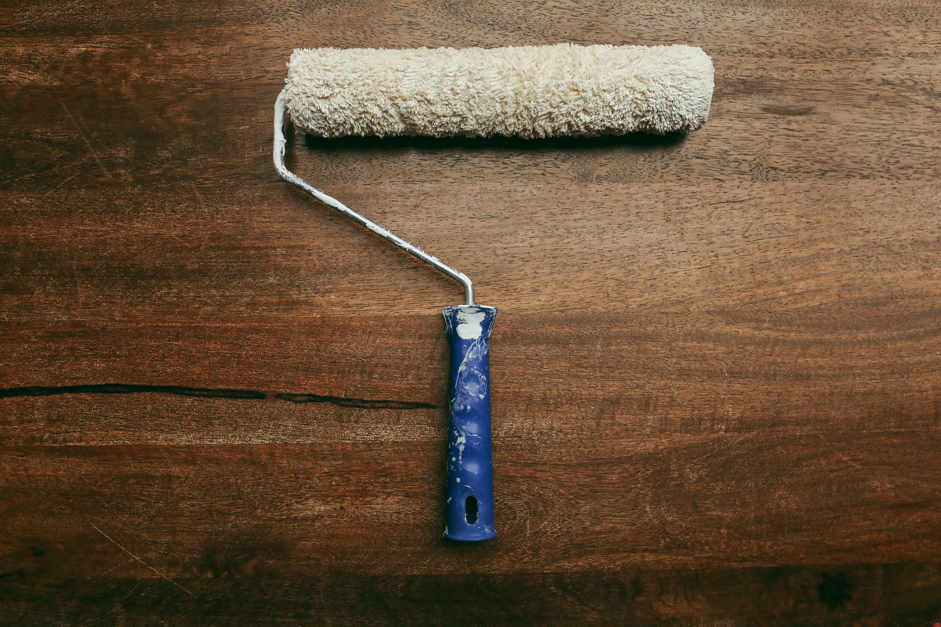 A worn paint roller placed on a wooden surface, ideal for DIY home improvement visuals in Temecula, CA